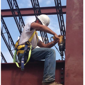 Steel erector sitting on a steel beam bolting beams and columns together